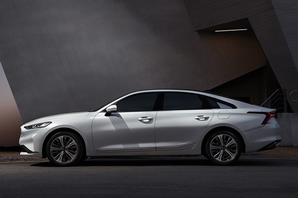 کیا K8 هیبرید سغید از بغل روی آسفالت با پس‌زمینه تیره