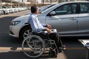 یک مرد مسن نشسته روی ویلچر در حال نگاه کردن به ماشین در پارکینگ
