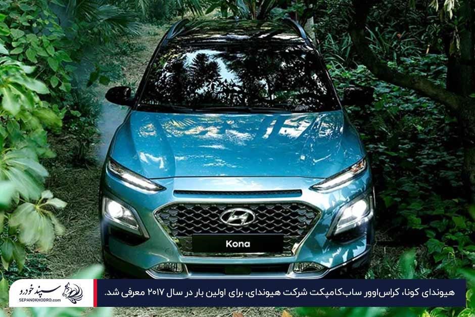 عکس نمای جلویی هیوندای کونا آبیرنگ پارکشده در یک جاده جنگلی
