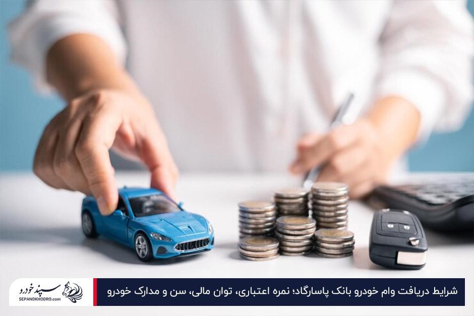 فردی در حال جابهجایی یک ماشین اسباببازی آبیرنگ در کنار سکهها و سوییچ خودرو روی میز